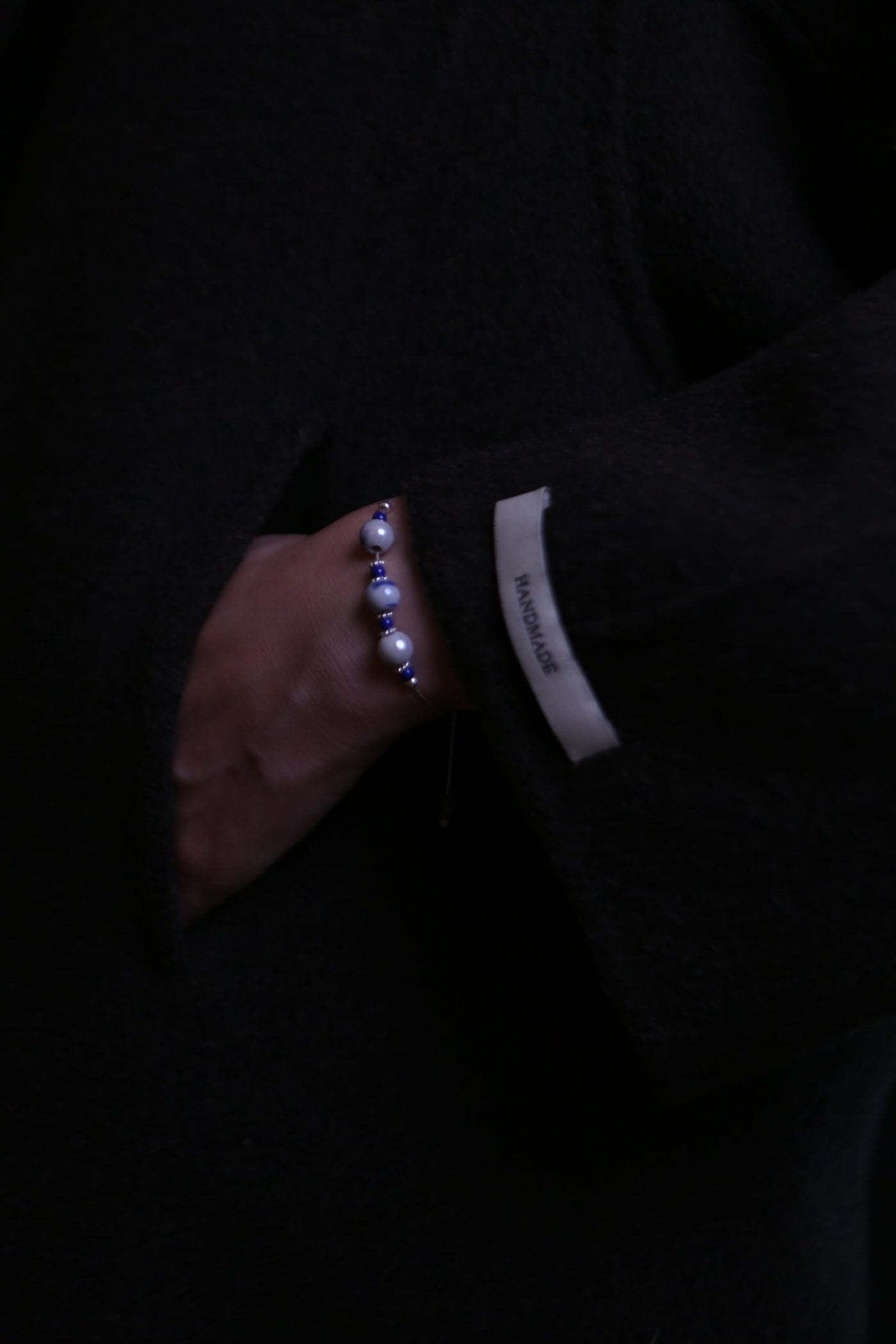 Blue porcelain preview bracelet worn with dark textured sleeve